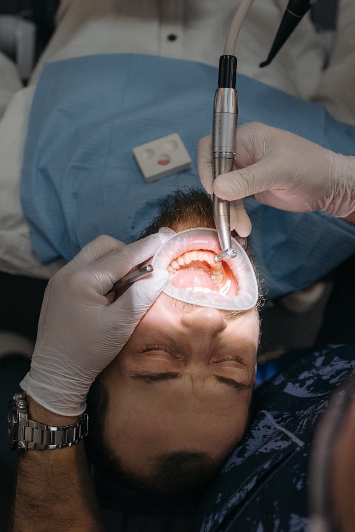 Close-up of a dental procedure with a patient's mouth open and cheek retractor in use.